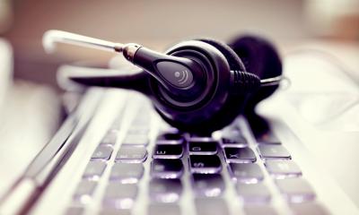 Set of black headphones with a microphone on top of a black keyboard