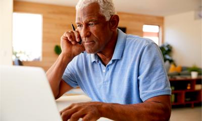 Entrepreneur using his smartphone, laptop and tech to run his business