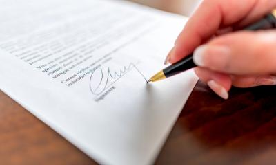 A person placing their signature at the botton of an IT support contract