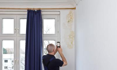 A man takes a digital photo of a mouldy wall