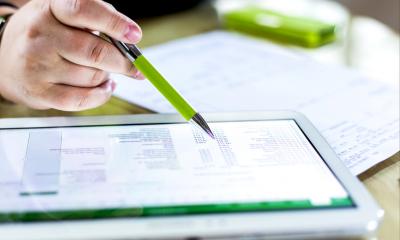 Closeup of a man holding a green pen pointing at his iPad