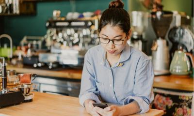 Coffee shop owner reading about potential bank loans while waiting for clients