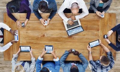 Group of staff sat around a table using their tech devices