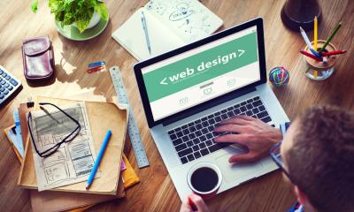 Overhead shot of web designer working on his laptop at a busy desk