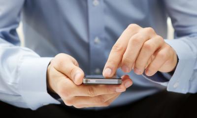 Communications A business man keeps in touch with his colleagues using instant messaging on his mobile device