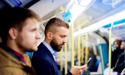 A businessman looks at his smart phone during a long commute