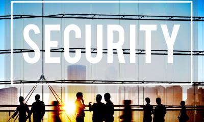 Silhouettes of people stood in front of panels of glass with 'SECURITY' written above them