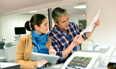 An entrepreneur examines a printout from a digital printer in the workplace.