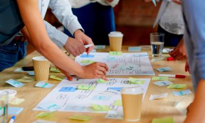 Group of people collaborating together and putting sticky notes down on the table