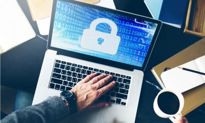 Man with a watch on using his laptop showing a blue screen with a padlock on it