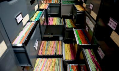 Multiple different filing cabinets with multicoloured documents in the drawers