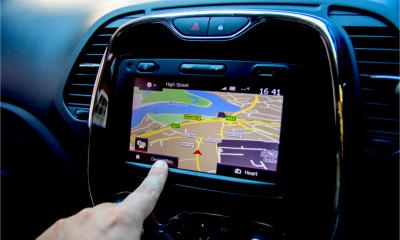 A hand is operating an in car GPS SATNav system