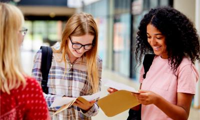 Three smiling female students open their exam results