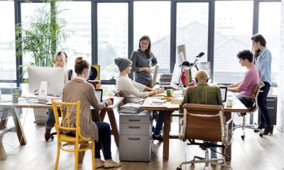 Multiple people sat at different desks working on computers in an office