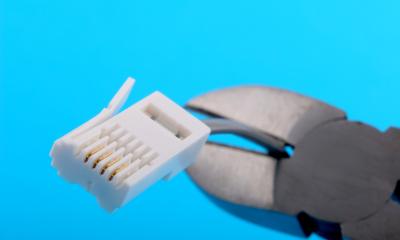 Pair of wire cutters cutting a broadband cable with a blue background