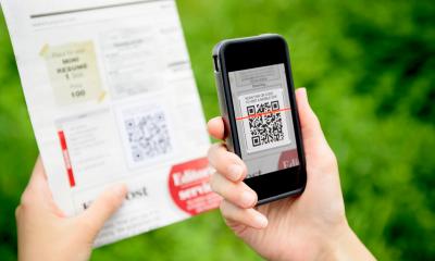 Person using their phone to scan the QR code on a piece of paper