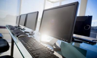 A row of computer screens and key boards in an office
