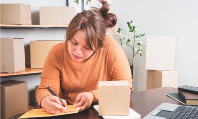 Young business owner wearing an orange jumper sorting out her next steps for her business