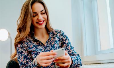 Woman sitting near window and checking her messaging app on her phone.