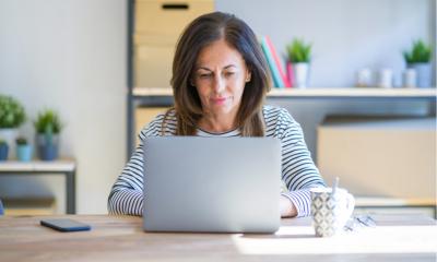 Middle age senior woman sitting at the table at home working using computer laptop Relaxed with serious expression on face