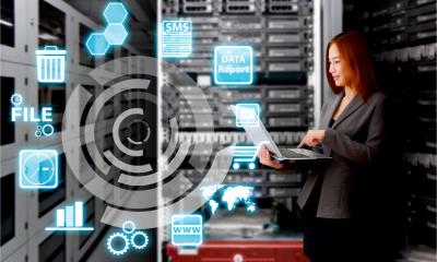A businesswoman works in a data centre surrounded by servers.