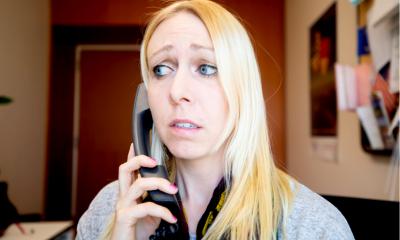 A young woman looks worried when she answers the phone in her office