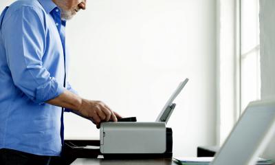 Bearded man in a blue shirt using a printer
