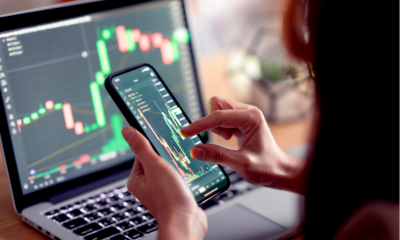 Woman checking the stock prices of cryptocurrency on her phone and laptop