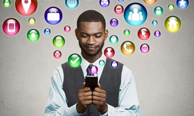 Man in a shirt and grey waistcoat holding his phone with apps surrounding his head