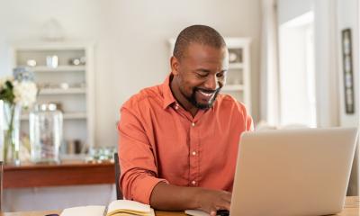 Smiling freelancer using laptop at home in living room